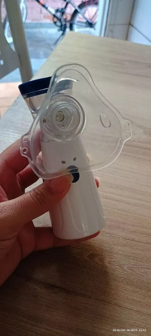 Nebulizador portátil con mascarilla sostenido en la mano